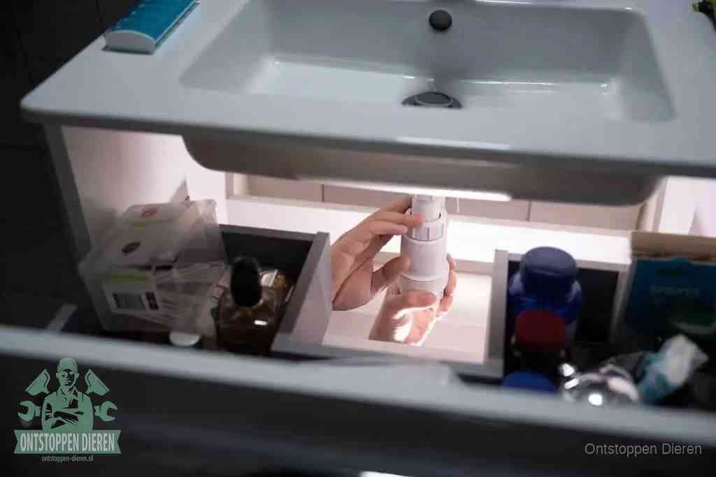 Een pompfles met zeep boven een wastafel, de heet water en afwasmiddel-methode om een vetprop in de afvoer los te maken in Dieren