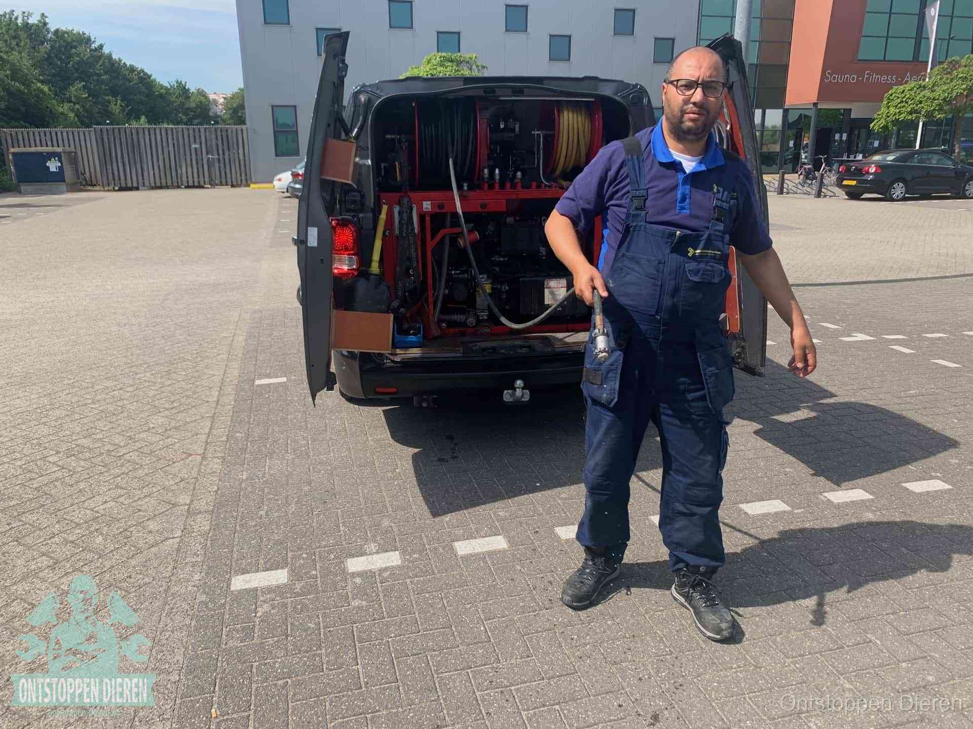Een monteur bij zijn bestelbus met een hogedruk- en rioolreinigingsunit, klaar om de oorzaak van terugkerende wc-verstoppingen aan te pakken in Dieren