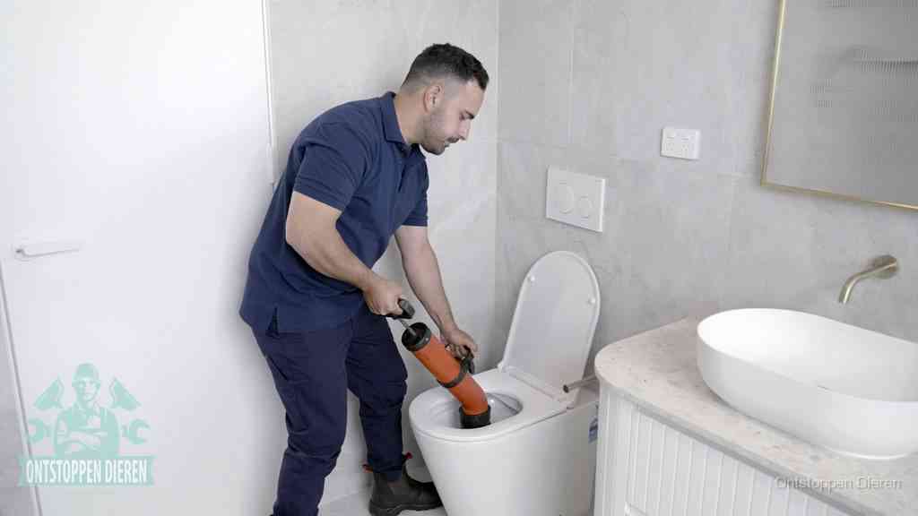 Een monteur gebruikt een handmatige perspomp (toiletontstopper) op een wandcloset tijdens het professioneel wc ontstoppen in Dieren