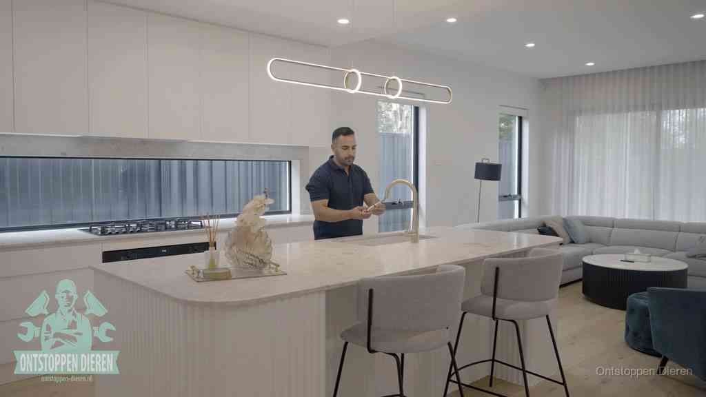 Een bewoner bij de keukenspoelbak die zelf aan de slag gaat met een verstopte gootsteen in Dieren